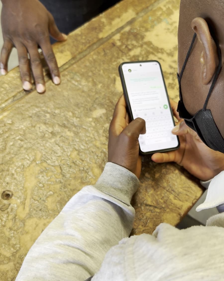A learner using WhatsApp on a phone at a school desk